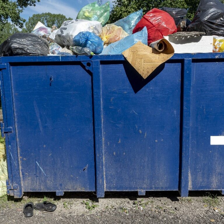 blue large mixed waste container next to a rail