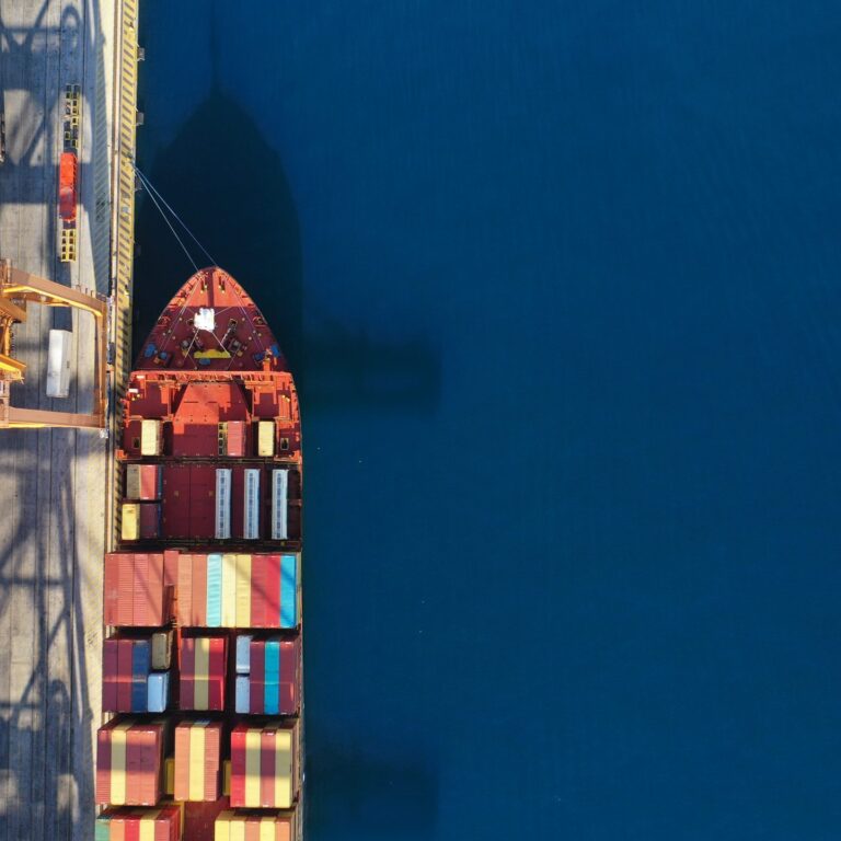Aerial drone top down photo of industrial cargo container tanker ship carrier docked in commercial port terminal
