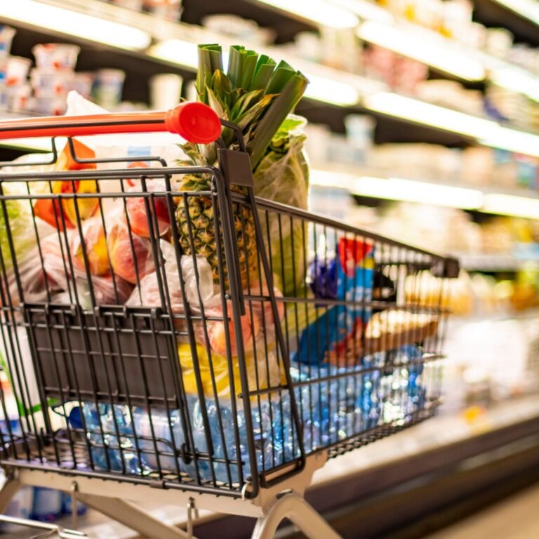 A shopping cart with grocery products in a supermarket
