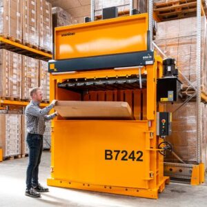 man loading cardboard into large commercial baler
